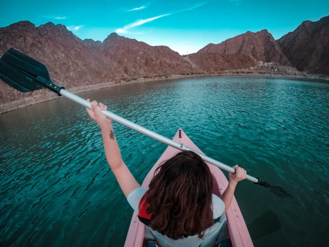 a girl with a paddle on a canoe floats on the lake