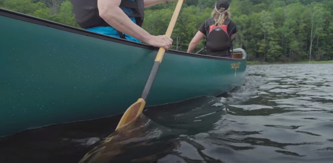 Canoe seen from below on water with two people riding