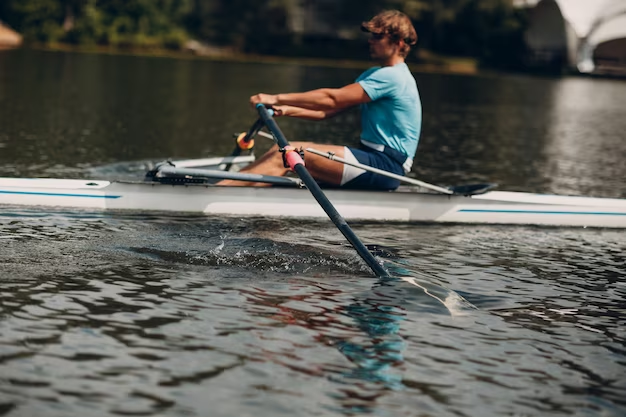 Man in sunglasses and hat paddling a canoe