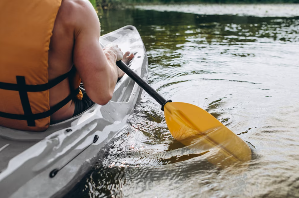 Young man in swimming vest kayaking on the river