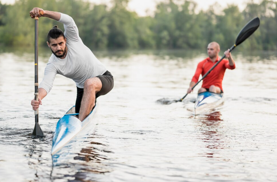 two men on kayaks with paddles, one is half-standing